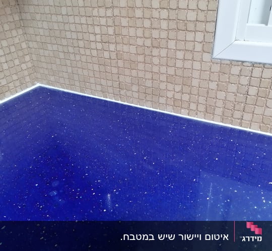 משטח שיש כחול מבריק עם קיר אריחים בהיר